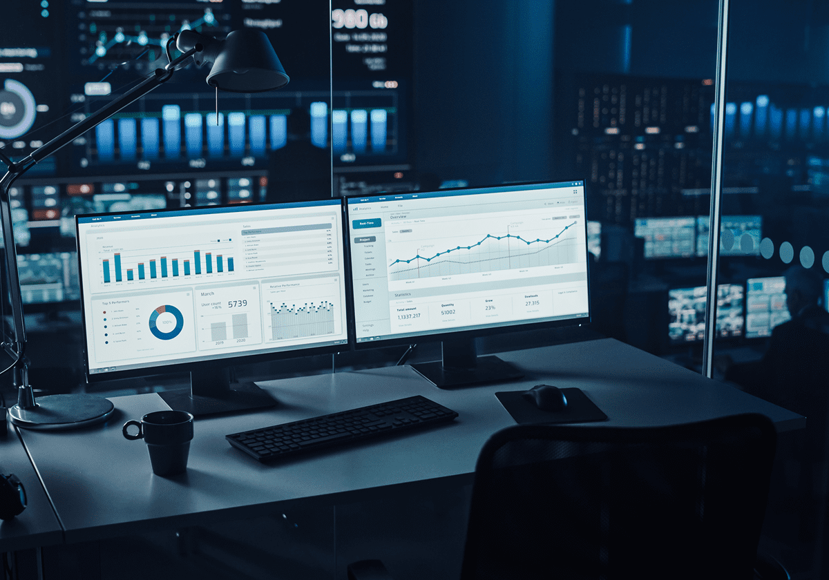 Dual monitors displaying data and charts.