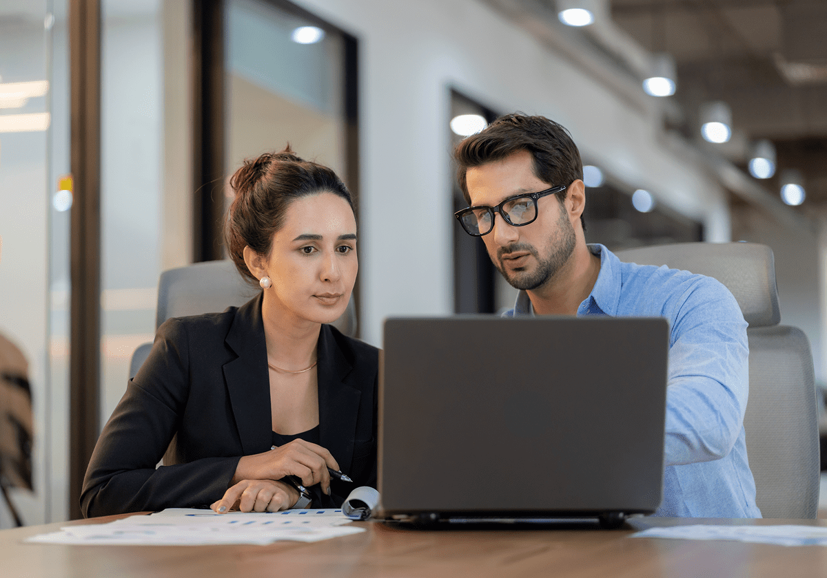 Two colleagues discussing work at laptop.