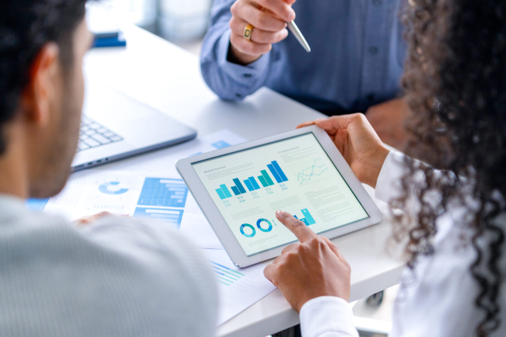 People analyzing data on a tablet screen.