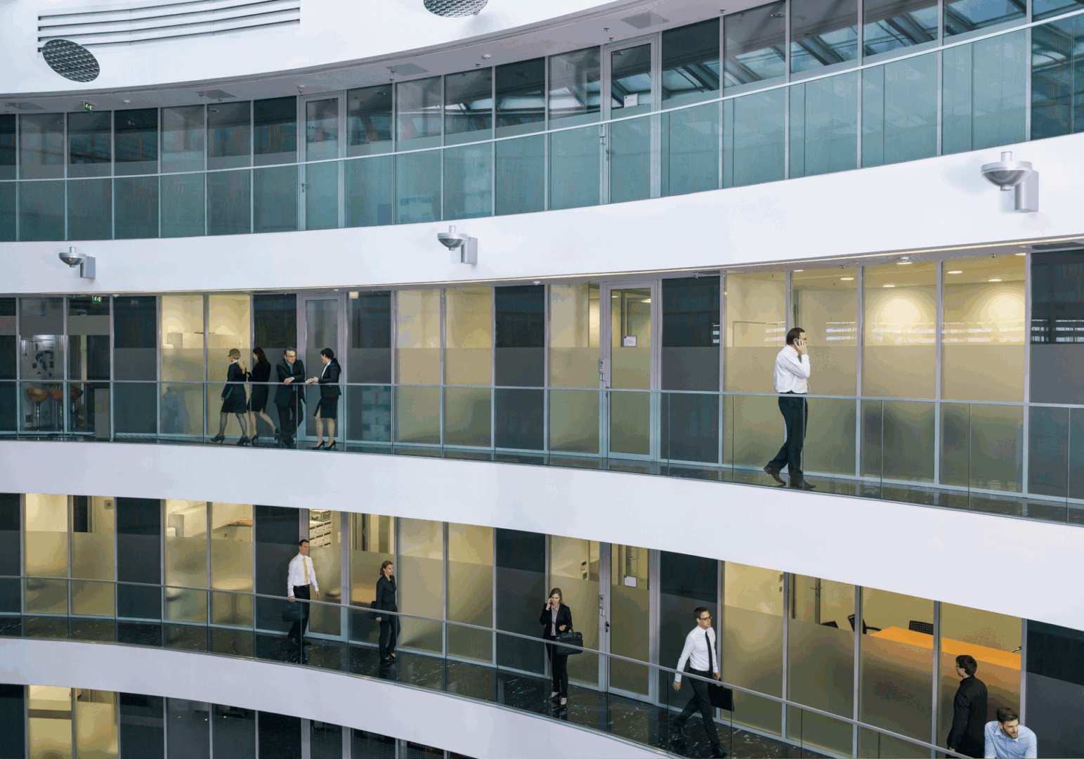 People walking in modern office building hallway.